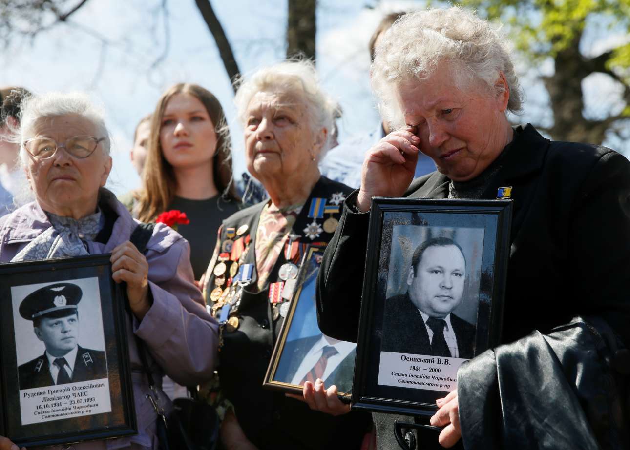 Γυναίκες κρατούν φωτογραφίες των συζύγων και άλλων συγγενών τους, θυμάτων της καταστροφής, στην αναμνηστική τελετή που πραγματοποιήθηκε στο Κίεβο, στις 26 Απριλίου